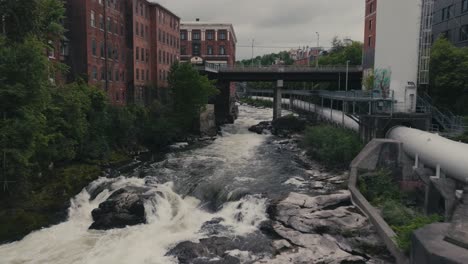 Water-Flowing-From-River-Dam,-Magog-River,-Sherbrooke,-Canada---Aerial-Drone-Shot