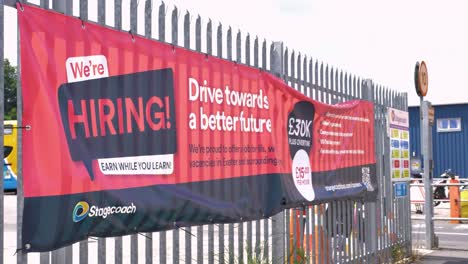 Stagecoach-hiring-banner-displayed-on-a-fence-promoting-job-opportunities,-Exeter,-Devon,-UK,-July-2024