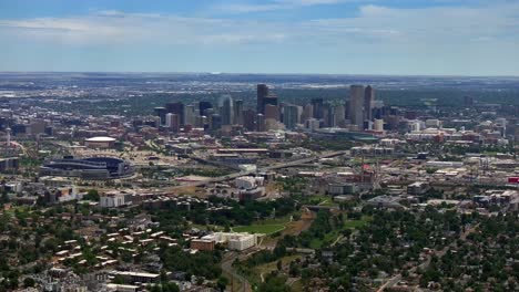 Summer-downtown-Denver-Colorado-aerial-drone-Mile-High-city-skyscrapers-neighborhood-homes-blue-skies-cloudy-6th-avenue-colfax-RTD-line-front-range-foothills-landscape-backwards-motion