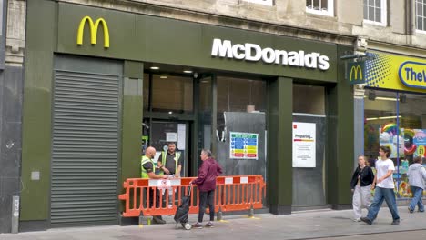 Exterior-of-new-high-street-McDonald's-under-construction-with-workers-and-safety-measures,-Exeter,-Devon,-UK,-July-2024