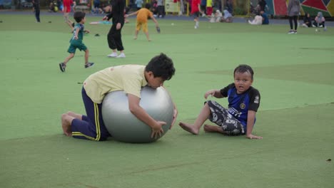 Niños-Divirtiéndose-Jugando-Con-Una-Pelota-Grande-En-El-Césped-De-La-Plaza-Ahmad-Yani-En-La-Ciudad-De-Tangerang,-Indonesia