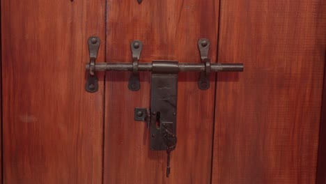 Rustic-wooden-door-with-an-old-metal-lock-and-latch-in-close-up-view