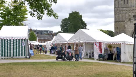 City-market-with-stalls-and-visitors-outside-Exeter-Cathedral,-Exeter,-Devon,-UK,-July-2024