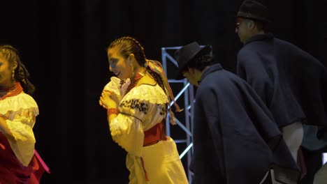 Traditional-dance-of-the-otavalo-culture,-andean-folklore,-Ecuador,-group-of-man-and-woman-wearing-cultural-costumes-and-performing-happily-on-the-stage