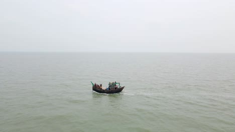 A-fishing-boat-packed-with-people-sails-across-the-ocean-on-a-hazy-morning