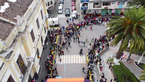 Editorial,-Top-angle-drone-shot-of-traditional-donkey-race,-central-park-of-Machachi,-Ecuador,-spectators-standing-on-the-side-of-the-road-and-watching-the-race-to-complete