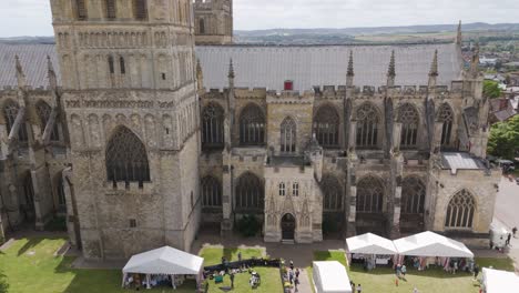 Majestic-aerial-flyby-capturing-the-intricate-medieval-gothic-architecture-of-Exeter-Cathedral-in-Exeter,-Devon,-under-a-clear-July-sky,-July-2024