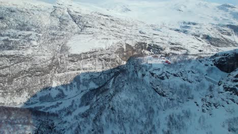 Epic-aerial-view-of-Norwegian-snowy-mountains-in-Myrdal-village,-drone-tilt-up-reveal-sky,-Scandinavian-winter