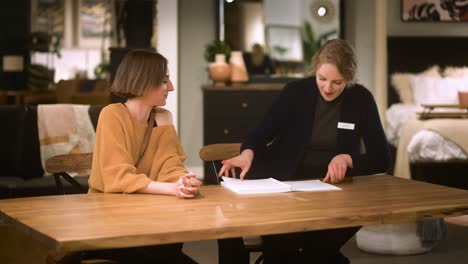 Customer-waits-at-dining-table,-salesperson-sits-with-quote-book,-explains-order-details