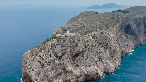 Impressive-aerial-view-of-lighthouse-tower-on-rugged-cliff-edge,-Mallorca