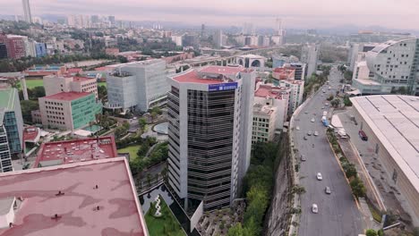 Volando-Entre-Edificios-Hacia-El-Centro-Comercial-Garden-Santa-Fe-Con-Sus-Conos-De-Vidrio-Y-Su-Plaza-Verde-En-La-Ciudad-De-México