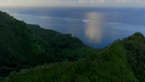 Teahupoo-Tahiti-bay-shoreline-sunrise-yellow-golden-hour-sunset-aerial-drone-view-from-mountain-peaks-to-coral-reef-French-Polynesia-WSL-Surfing-summer-Olympic-venue-town-village-forward-pan-up-motion