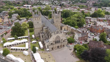 Drone-orbital-of-Exeter-City-Cathedral-with-lively-market-stalls,-highlighting-the-architectural-beauty-in-Exeter,-Devon,-UK,-July-2024