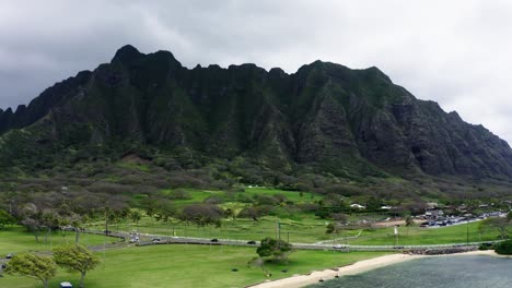 Drone-shot-of-the-Kualoa-Ranch-mountains-and-surrounding-forests-lining-the-Hawaiian-highway