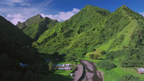 Towering-mountains-valley-river-Teahupoo-Tahiti-aerial-drone-French-Polynesia-South-Pacific-island-volcano-bright-morning-afternoon-sunny-green-lush-bluesky-WSL-surfing-Olympic-venue-forward-up-reveal