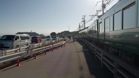 Caminando-Junto-Al-Famoso-Tren-Enoden-Con-Vista-Hacia-La-Isla-De-Enoshima