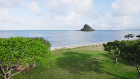 An-idyllic-view-of-Mokoli'i-Island,-also-known-as-Chinaman's-Hat,-from-a-lush-green-beach-park-in-Oahu