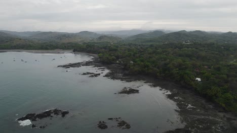 Santa-catalina,-panama-coast,-with-lush-greenery-and-rocky-shoreline-on-a-cloudy-day,-aerial-view