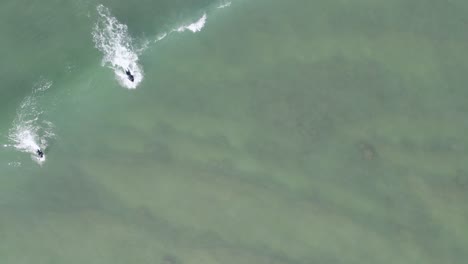 Surfers-in-black-wetsuits-paddle-towards-the-rising-wave-they-surf-in-the-sea