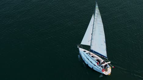 Aerial-view-of-a-sailboat-navigating-in-Lake-Maggiore,-Italy