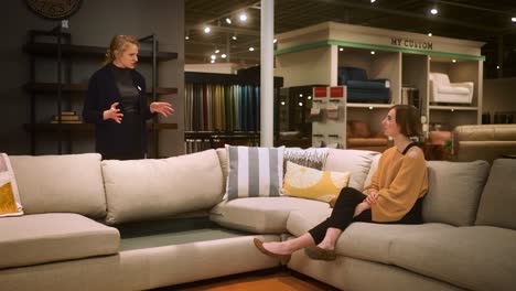 Salesperson-explains-sofa-details-to-seated-customer-in-furniture-store-dolly-shot