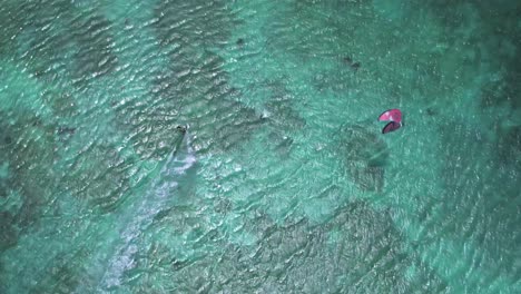 A-kite-surfer-gliding-over-turquoise-waters,-aerial-view