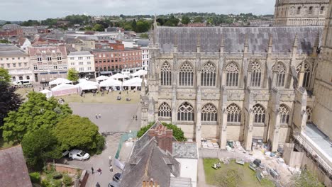 Breathtaking-aerial-reveal-of-the-historic-Exeter-City-Cathedral,-highlighting-its-grand-gothic-structure-against-the-backdrop-of-Exeter,-Devon,-UK,-July-2024