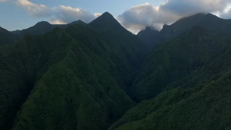 Teahupoo-Tahiti-across-mountain-peaks-valley-hills-coastline-sunrise-yellow-clouds-golden-hour-sunset-aerial-drone-view-French-Polynesia-WSL-Surfing-summer-Olympic-venue-town-village-forward-pan-up