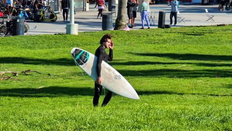 Surfista-Masculino-Con-Tabla-De-Surf-Yendo-A-La-Playa,-Venice-Beach,-Los-Ángeles,-Estados-Unidos