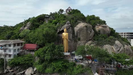 Tall-golden-standing-Buddha-statue-on-side-of-Monkey-Mountain,-Hua-Hin,-Thailand