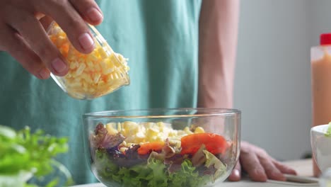 A-Man-Making-Salad,-Pouring-Corn-Kernels-On-Other-Vegetables-In-Salad-Bowl