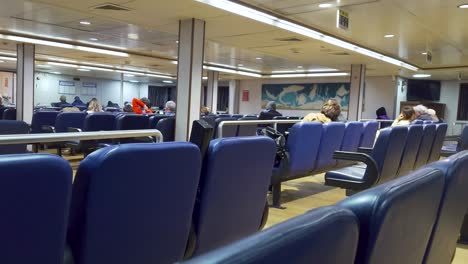 People-sitting-in-an-elegant-lounge-inside-a-ferry-with-rows-of-comfortable-blue-seats---Naples,-Italy