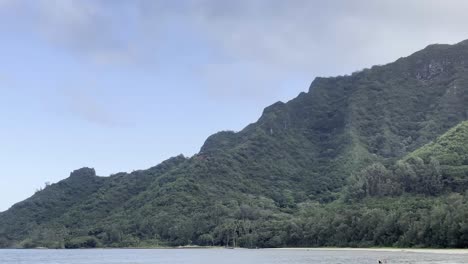 A-peaceful-scene-of-Oahu's-lush,-green-coastline-meeting-the-calm-blue-waters-of-the-Pacific-Ocean-under-a-clear-sky