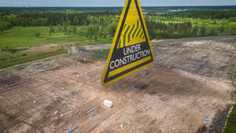 Gran-Proyecto-De-Construcción-En-Terrenos-Recién-Despejados-En-El-Campo---Hiperlapso-Aéreo-Con-Animación-Gráfica-De-Advertencia-De-Triángulo-Amarillo