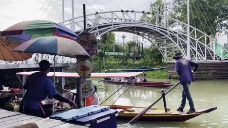 Touristen-Genießen-Das-Thailändische-Essen-Auf-Dem-Schwimmenden-Markt-Und-Fahren-Mit-Einem-Traditionellen-Holzboot-Durch-Den-Kanal