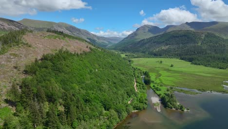 Wide-green-valley-with-lake-shore,-forested-and-deforested-hillsides-and-mountains