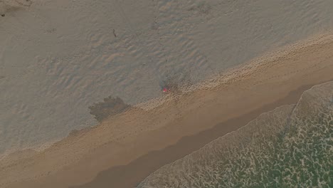 Top-down-shot-of-a-person-standing-on-the-beach-at-Noordhoek-during-sunset