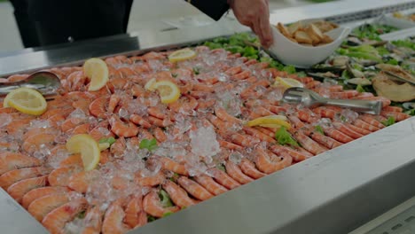 Mesa-De-Buffet-Con-Una-Muestra-De-Camarones-Frescos-Sobre-Hielo-Adornados-Con-Rodajas-De-Limón,-Resaltando-La-Elegancia-Del-Marisco