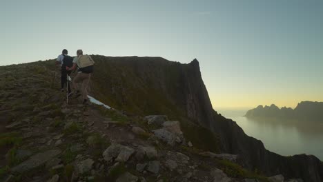 Pareja-Joven-Subiendo-Una-Montaña-En-Senja,-Noruega-Durante-El-Amanecer