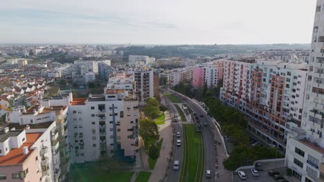 Aerial-view-following-a-road-in-middle-of-colorful-buildings-in-Almada,-Portugal