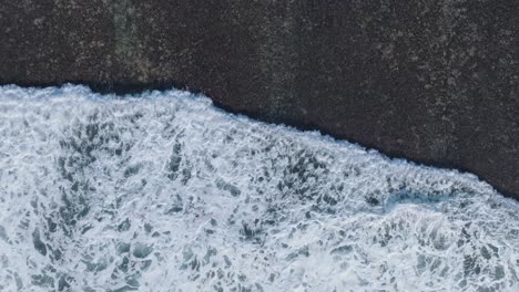 Von-Oben-Nach-Unten-Aufgenommene-Drohne-Verfolgt-Die-Wellenbewegung-über-Dem-Korallenriff-In-Uluwatu,-Bali,-Indonesien