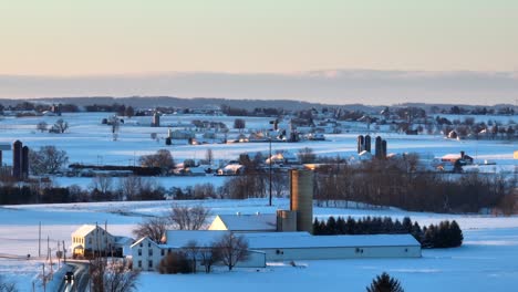 Aerial-wide-shot-of-snowy-winter-landscape-during-golden-sunrise