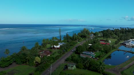 Teahupoo-Tahiti-French-Polynesia-aerial-drone-view-road-van-car-up-island-parallel-to-coast-to-Papeete-morning-sunny-bay-channel-coral-reef-mountains-traffic-roadtrip-drive-forward-pan-up-reveal