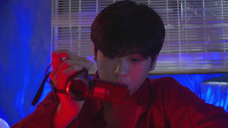 asiatic-male-looking-at-display-of-his-retro-vintage-record-camera-player-while-drinking-alcohol-forgetting-memories-after-heart-broking-concept