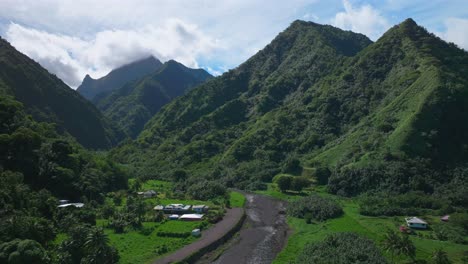 Towering-mountain-volcano-peaks-valley-rivers-Teahupoo-town-Tahiti-French-Polynesia-Moorea-Papeete-aerial-drone-stunning-island-late-morning-afternoon-blue-sky-daytime-sunny-clouds-forward-pan-up