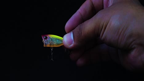 Hand-holding-artificial-lure-of-mini-popper-with-black-background