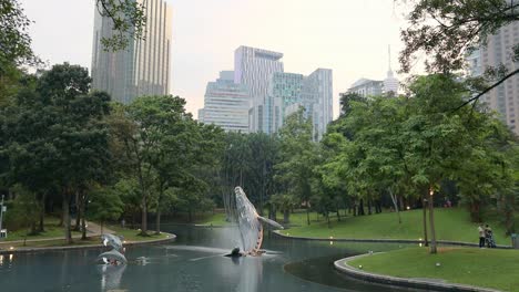 Whale-statute-and-pond-wide-angle-at-Suria-KLCC-Park,-Kuala-Lumpur,-Malaysia,-during-the-evening