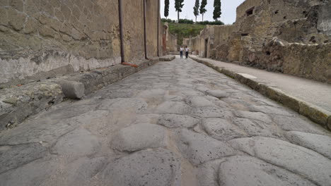 Tourists-walk-along-a-cobbled-street-in-the-historical,-ancient-Roman-city-of-Herculaneum