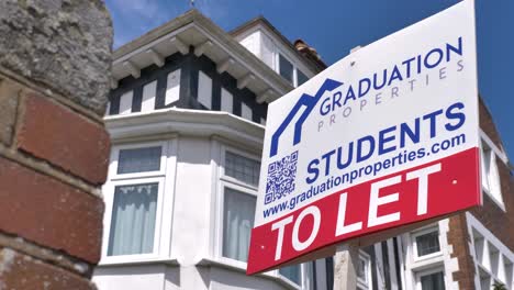 Reveal-of-estate-agent-sign-for-student-properties-against-backdrop-of-urban-residential-area,-Exeter-Devon-UK,-June-2024