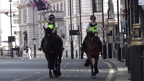 Two-female-mounted-police-officers-ride-down-Whitehall-towards-the-Houses-of-Parliament